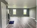 Open living room with hardwood floors, gray walls, and lots of natural light from the three windows at 215 Traditions Pass, Greenwood, IN 46143