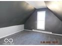 A quiet attic space with neutral color walls, a window, and carpet flooring at 711 W Centennial Ave, Muncie, IN 47303