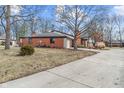 A brick home showing the driveway, landscaping, and roof, complemented by mature trees at 9277 Golden Leaf Way, Indianapolis, IN 46260