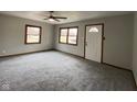 A living room featuring carpeted floors, three windows, neutral walls, and a ceiling fan with lighting at 13421 Miller Dr, Camby, IN 46113