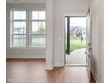 Bright entryway featuring hardwood floors, large windows, and a view of the home across the street at 15871 Vitalize Run, Fishers, IN 46040