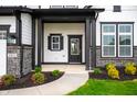 Inviting front porch with decorative stone accents, manicured flower beds, and an elegant front door at 15871 Vitalize Run, Fishers, IN 46040