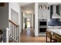 Bright hallway featuring hardwood floors, a staircase, and entry to the modern kitchen at 15871 Vitalize Run, Fishers, IN 46040
