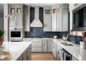 Modern kitchen featuring gray cabinets, stainless steel appliances, and a blue tile backsplash at 15871 Vitalize Run, Fishers, IN 46040