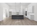 Bright kitchen featuring white cabinets, gray island, modern lighting, and hardwood flooring at 17364 Pinellas Ave, Westfield, IN 46074
