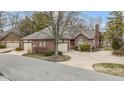 Traditional brick house with attached garage, well-kept landscaping, and a curving concrete driveway at 2042 Oldfields Cir N Dr, Indianapolis, IN 46228