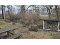 View of the backyard with a creek, picnic table, and covered firewood storage area for outdoor enjoyment at 2455 Endsley Dr, Indianapolis, IN 46227