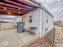 View of back exterior with concrete patio, grill, trash can, and some lawn equipment at 2959 N Lasalle St, Indianapolis, IN 46218