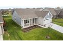 A cozy home featuring manicured lawn and landscaping, complemented by a quaint front porch with seating at 602 Tuscany Trl, Lapel, IN 46051