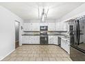 Bright kitchen with tile floors, white cabinets, stainless steel appliances, and modern lighting at 714 School St, Greenfield, IN 46140