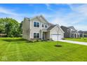 Inviting two-story home with a lush lawn, landscaping, and attached two-car garage at 7168 Jackson Dr, Cumberland, IN 46229