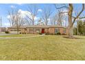 Traditional brick home featuring a red front door and well-maintained lawn at 7481 Holliday E Dr, Indianapolis, IN 46260
