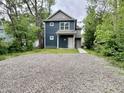 Two-story home with gravel front yard and blue siding surrounded by mature trees at 859 N Oakland Ave, Indianapolis, IN 46201