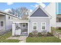Charming home with a gabled roof, covered porch, tidy landscaping, and freshly painted gray siding at 1210 S State Ave, Indianapolis, IN 46203