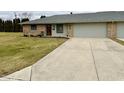 View of charming brick home, driveway, and manicured front lawn, with attached garage at 1408 Lawrence Way, Anderson, IN 46013