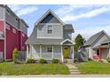 Attractive two-story home boasts a covered front porch, cheerful yellow door, and manicured lawn at 1724 Prospect St, Indianapolis, IN 46203