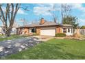 Well-maintained brick home with an attached garage and a lush green lawn in a residential area at 4905 N Dearborn St, Indianapolis, IN 46205