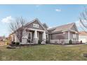 Stylish gray home shows manicured lawn with stone accents and features a welcoming covered front porch at 5955 Stroup Dr, Noblesville, IN 46062