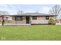 Charming brick home featuring a covered porch and manicured front lawn at 714 S 4Th Ave, Beech Grove, IN 46107