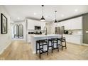 Bright kitchen with white cabinets, stainless steel appliances, center island with barstool seating, and wood floors at 7346 Shroyer Way, Noblesville, IN 46062