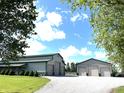 Exterior shot of a large barn with multiple garage doors and a well-maintained gravel driveway at 9615 N County Road 150 E Rd, Pittsboro, IN 46167