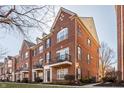 Brick townhome exterior with a private balcony, manicured lawn and mature trees at 100 11Th Nw St, Carmel, IN 46032