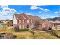Aerial view of a beautiful red brick home highlighting the manicured lawn and surrounding landscape at 13788 Four Seasons Way, Carmel, IN 46074