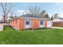 Side view of the red brick ranch home showcasing its well maintained lawn and classic design at 3125 Anniston Dr, Indianapolis, IN 46227