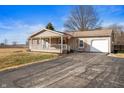 Inviting home featuring a cozy front porch, a freshly paved driveway, and beautiful landscaping at 3226 E 300 N, Anderson, IN 46012