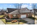 An aerial of a brick house with an attached two car garage, a yard and sidewalk near a tree filled area at 5115 Baltustrol Dr, Avon, IN 46123