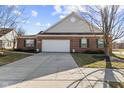 Traditional brick home featuring a two-car garage, manicured lawn, sidewalk, and beautiful architectural details at 5115 Baltustrol Dr, Avon, IN 46123