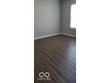 Clean and neutral bedroom featuring hardwood floors, a window for natural light, and painted walls at 5851 Brobeck Ln, Indianapolis, IN 46254