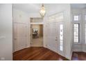 Bright foyer with hardwood floors and view into a home office, illuminated by a stylish pendant light at 7195 Koldyke Dr, Fishers, IN 46038