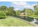 A backyard featuring a picturesque pond, black metal fencing, lush green grass and mature trees at 7645 Ballinshire N, Indianapolis, IN 46254