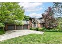 Charming brick home featuring a three-car garage and well-maintained landscaping, and a beautiful lawn at 7645 Ballinshire N, Indianapolis, IN 46254
