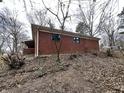 Side angle of a brick home with a covered porch and a backyard filled with dried leaves at 8328 S Franklin Rd, Indianapolis, IN 46259