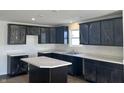 Well-lit kitchen featuring dark cabinetry, a large sink under the window, and a functional island at 10265 Cliff Ln, Indianapolis, IN 46239