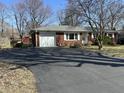 Red brick ranch-style home with attached garage and long asphalt driveway at 1031 Schleicher Ave, Indianapolis, IN 46229