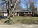 Charming red brick ranch-style home with attached garage, landscaped yard, and mature trees at 1031 Schleicher Ave, Indianapolis, IN 46229
