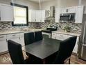 Bright kitchen with white cabinetry, mosaic backsplash, and stainless steel appliances at 318 Congress Ave, Indianapolis, IN 46208