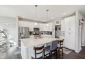 Bright eat-in kitchen featuring white cabinetry, stainless steel appliances, hardwood floors, and modern pendant lighting at 3203 S Cordell Rd, New Palestine, IN 46163