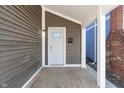 Inviting front porch with gray siding, white trim, and a white front door with glass at 569 N Tacoma Ave, Indianapolis, IN 46201