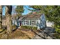 Quaint home featuring light blue siding, complemented by a detached garage and mature trees at 5935 Compton St, Indianapolis, IN 46220