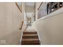 Carpeted staircase featuring decorative wrought iron railing and natural light from the landing window at 681 Greenford N Trl, Carmel, IN 46032