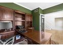 Office with custom wood built-ins, a large desk, green walls, and hardwood floors at 12396 Dellfield W Blvd, Carmel, IN 46033