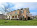 Two-story brick home showcases a spacious front yard with a covered porch and manicured landscaping at 4604 S Cobblestone Dr, Zionsville, IN 46077