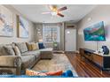 Inviting living room with hardwood floors, a comfortable sectional couch, and a modern ceiling fan at 5839 Beacon Cove Way, Indianapolis, IN 46237