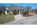 Single story home with a curved drive, lush green lawn, mature landscaping, and many beautiful arched windows at 6520 Forrest Commons Blvd, Indianapolis, IN 46227