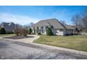 Wide front view of home with circular driveway, arched windows, mature trees, and lush lawn at 6520 Forrest Commons Blvd, Indianapolis, IN 46227