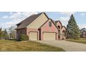 The right side of this red brick home showcases a two-car attached garage and pristine lawn at 7619 Bluebird Ct, Brownsburg, IN 46112
